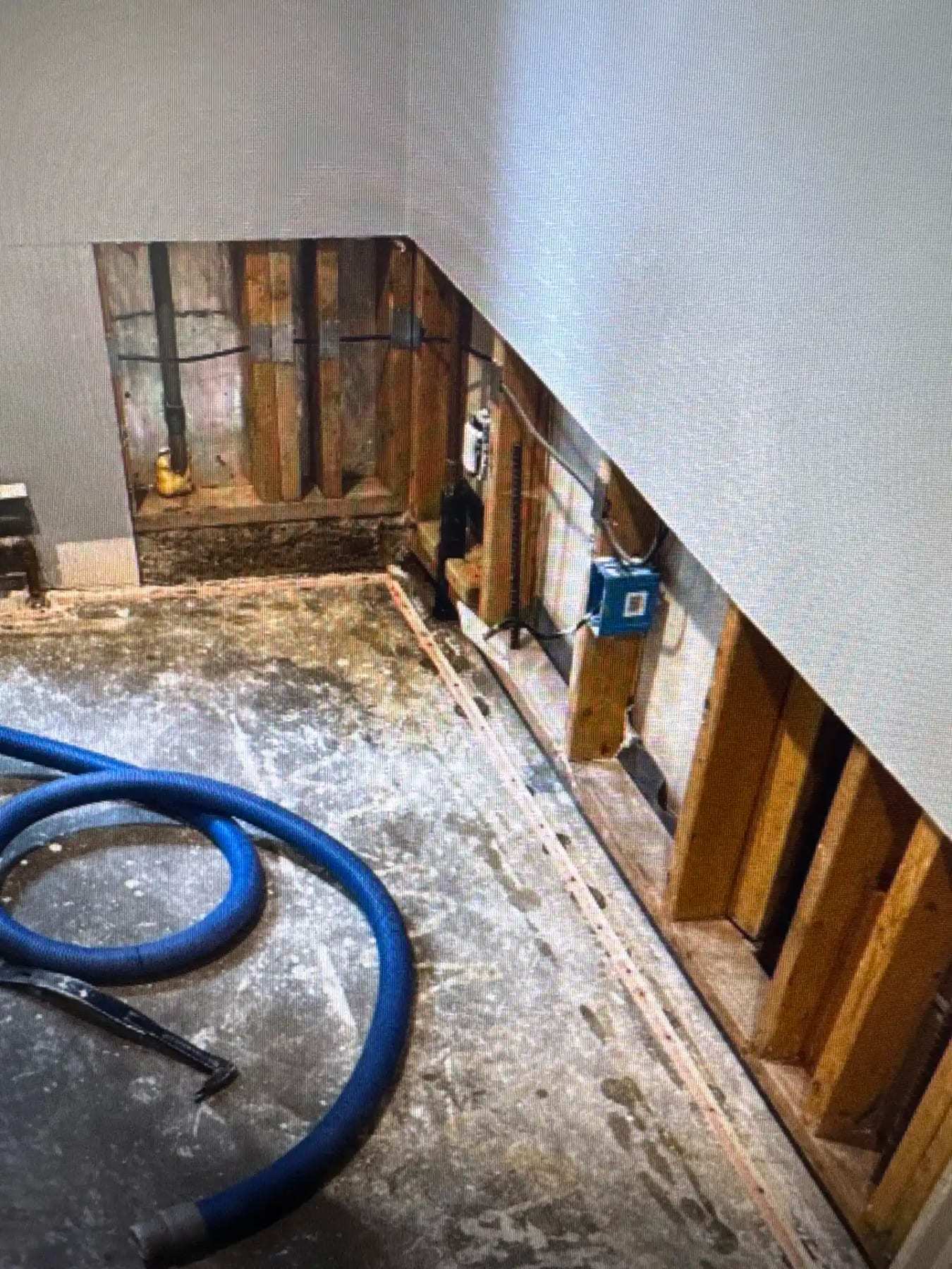 Bathroom demolished to the framing with drying hoses on the floor