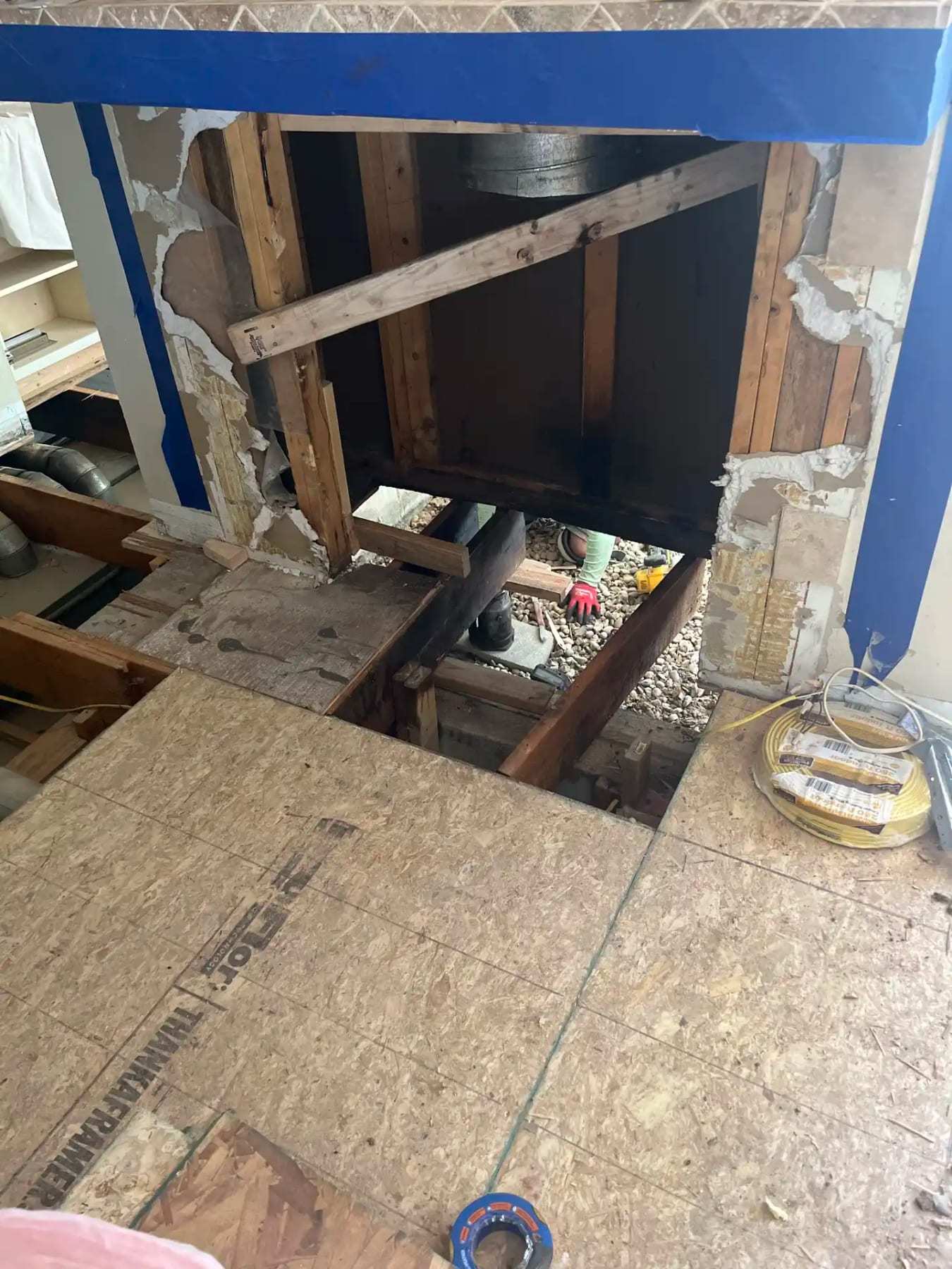Opening cut in a subfloor with plywood sheets and framing exposed